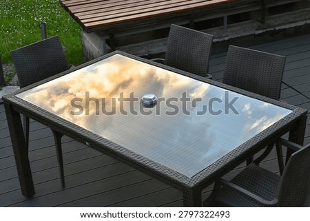 Reflection of clouds in the glass of a table with an ashtray
