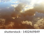 Reflection of clouds in the river. The sky in the rays of the setting sun. Beautiful sunset. Natural landscape.