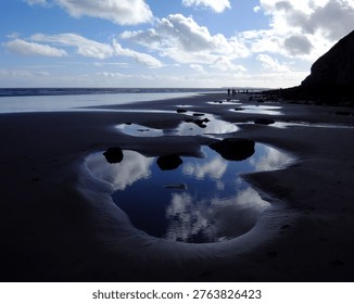 The reflection of clouds in the rockpools on the beautiful beach at Pendine, Carmarthenshire, Wales, UK.