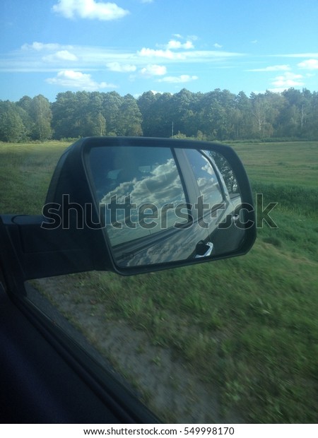 Reflection of cloudy sky in\
car mirror