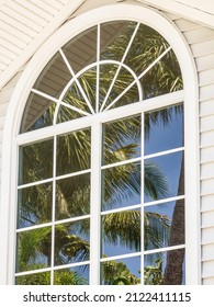 Reflection Of Coconut Tree (binomial Name: Cocos Nucifera) In Tall Arched Window Of Upscale House On An Island Off The Gulf Coast Of Florida