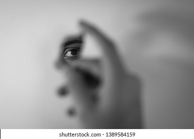 reflection of an eye in a broken mirror held by a hand - Shutterstock ID 1389584159