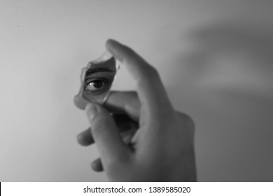 reflection of an eye in a broken mirror held by a hand - Shutterstock ID 1389585020