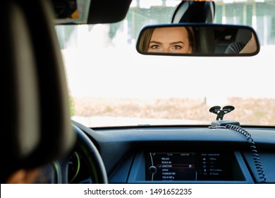 Reflection Of Female Eyes In Rearview Mirror Of A Car