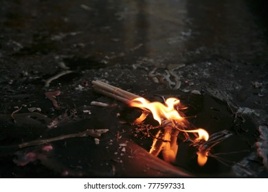 Reflection Of The Flame Of A Bunch Of Ritual Wax Candles In A Puddle On The Ground. India.