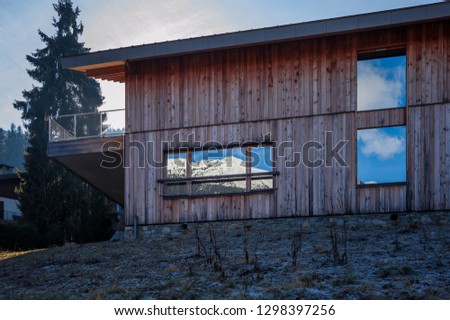 reflection of the french alps in mirrored stained glass windows in a wooden modern chalet in chamonix