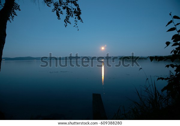 Reflection of the full moon in a lake water. Night\
landscape. Scenic nature\
scene