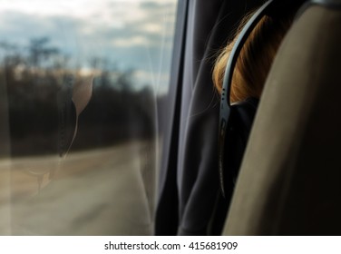 A Reflection Of A Girl With Headphones In The Bus Window. Back View. Close-up. On The Sunset.