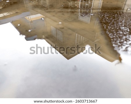 Reflection of house in puddle on pavement