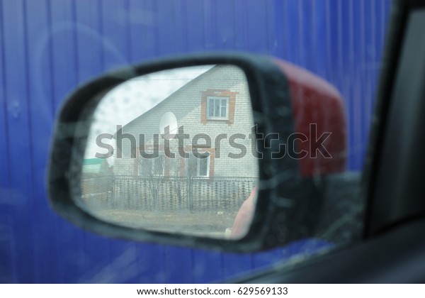 Reflection of a\
house in a side mirror of a\
car.