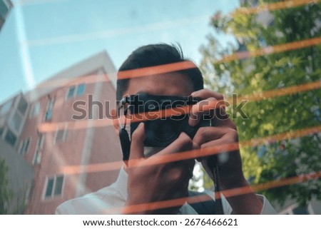 Reflection of man taking photo with camera through glass window.