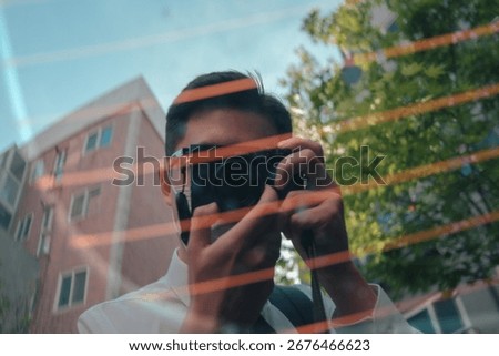 Reflection of man taking photo with camera through glass window.