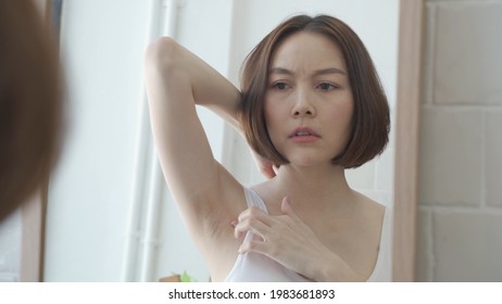 reflection mirror Asian female worry about black armpit with hair growing in bathroom at home. dark underarms concept. short hair woman looking mirror concern worried and Lack of confidence. problem.