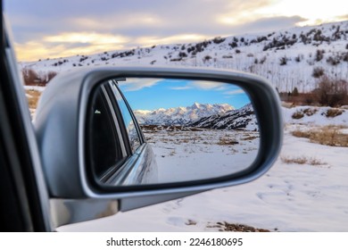 Reflection in the mirror of a car of beautiful snow-capped mountains and roads - Shutterstock ID 2246180695