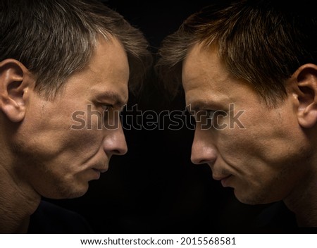 reflection in the mirror, doubt versus confidence, portrait of a man with different emotions, on a black background