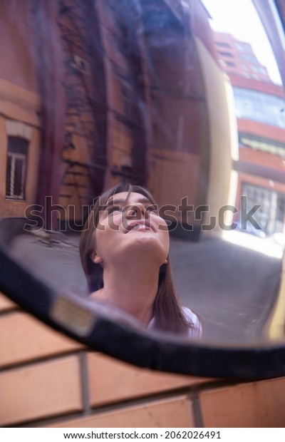 Reflection in the mirror of european woman outside\
in an industrial\
area