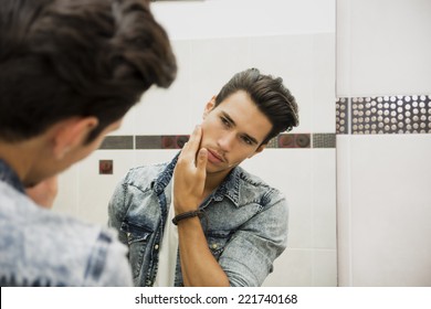 Reflection In Mirror Of Man Touching Face As If Examining Quality Of Shave Or Skin