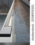 A reflection of a modern skyscraper with a grid-like facade captured in the water of the 9.11 Memorial pool in New York City. The perspective highlights the juxtaposition of stillness and flow