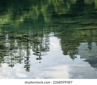 Reflection in the mountain lake of coniferous forest and mountain landscape, clear mountain lake as a mirror
