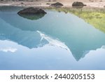 Reflection of a mountain range with snowfields and glaciers in the blue water of Lake Kulikalon in the Fan Mountains in the morning in Tajikistan, Tien Shan highlands