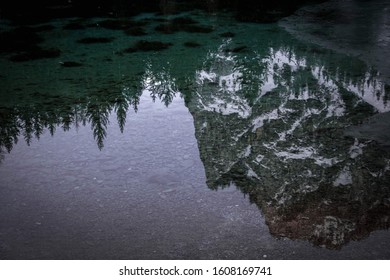 reflection of a mountain and trees in a small lake