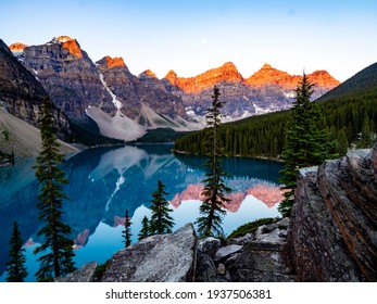 reflection of mountains in a turquoise lake early in the morning with red on the peak - Powered by Shutterstock
