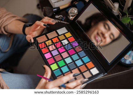 Reflection of a non-binary person in the mirror putting on makeup before going to work