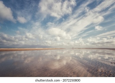 Reflection On A Beach In Southern Netherlands. Person Standing On The Beach.