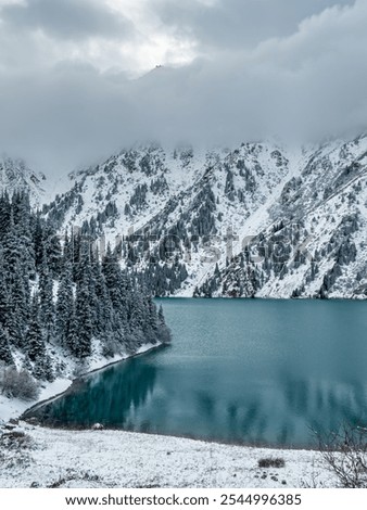 Reflection on mountains and trees covered with snow in Big Almaty lake in Kazakhstan