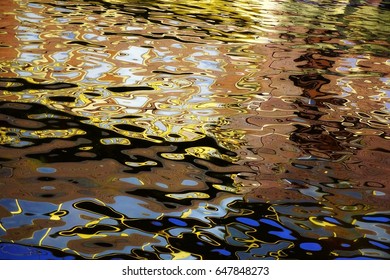 Reflection on surface of water, consisting of circles, ovals, abstract forms, colored spots, different rounded geometric shapes. Colors of the photo: blue, black, yellow, brown, white. Amazing place