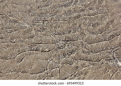 The reflection pattern of water on the sand.