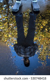 Reflection in a puddle of man framed by autumn leaves on a tree