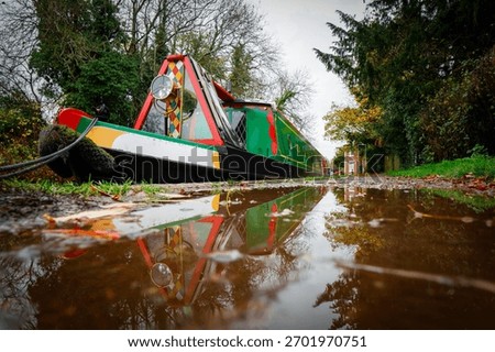 A reflection in a puddle of a narrowboat on a canal 