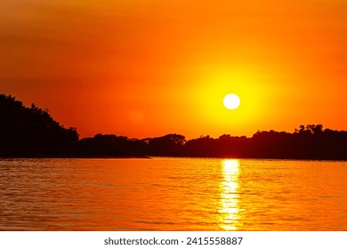 Reflection of the Rays of the sun as it rises over the river Cuiaba in the Pantanal in Brazil