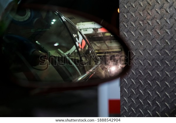 Reflection of the\
right side of the car in its side mirror, close-up view, dark\
blurred background of warm\
shades