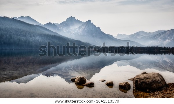 Reflection of Sawtooth Mountains on Red Fish Lake\
on foggy morning, Stanley,\
Idaho.