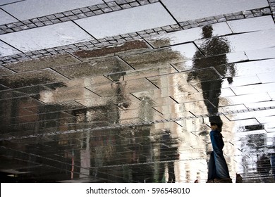 Reflection Shadow Of A Man Walking In The City Pedestrian Zone Just After The Rain