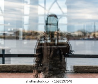 Reflection shot of a man standing in front of a window.