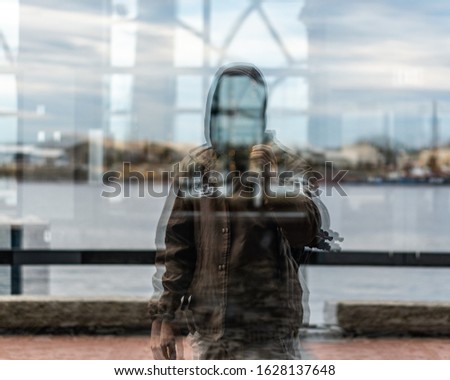 Reflection shot of a man standing in front of a window.