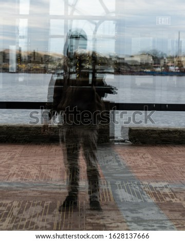 Reflection shot of a man standing in front of a window.