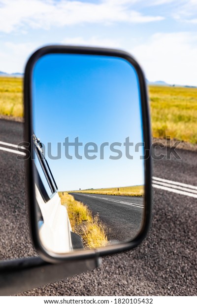 Reflection in a side mirror of a country road\
behind a 4x4 vehicle