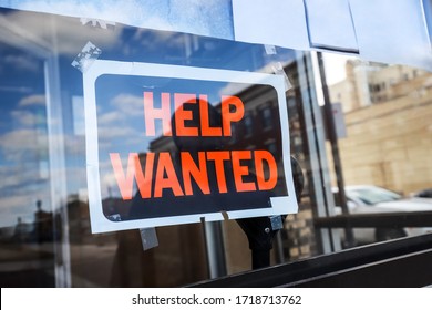 Reflection of a silhouette of a man looking at a help wanted sign in a business window, economy concept, shallow focus on middle of sign