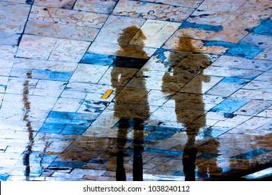 Reflection Silhouette Of Two Young Women Walking City Sidewalk On A Rainy Day With Vibrant Colors