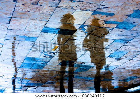 Reflection silhouette of two young women walking city sidewalk on a rainy day with vibrant colors