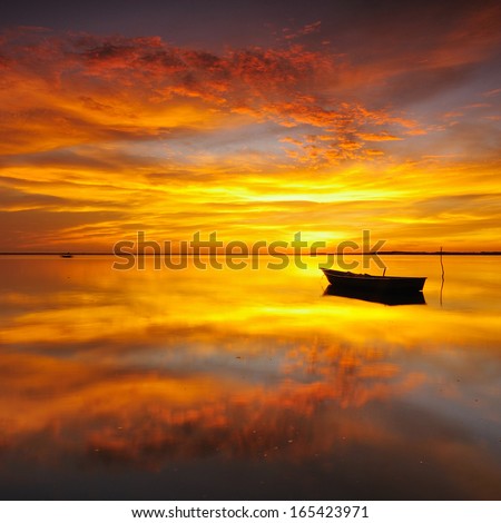 Reflection of Single Boat with Burning Sky During Sunrise/Sunset