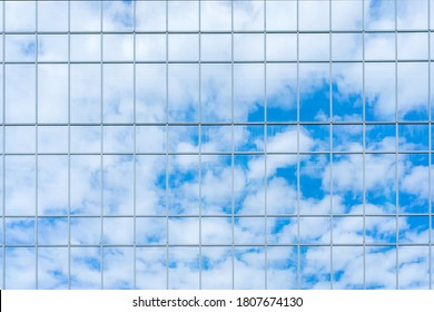 Reflection of the sky and clouds in the glass wall of a high-rise building. Glass wall of a skyscraper.
