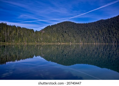 Reflection of the sky and jet trails in a still mountain lake