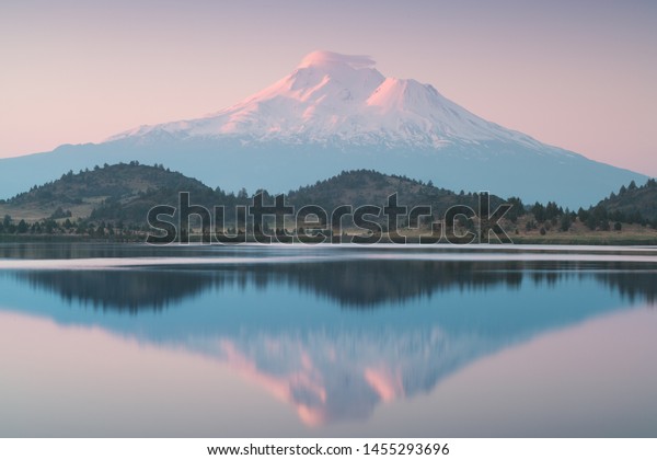 A reflection of snow capped Mount Shasta in a clear\
water in lake  at sunrise in California State, USA. \
Mount Shasta\
is a volcano at the southern end of the Cascade Range in Siskiyou\
County 