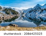 Reflection of the snowy mountains in the beautiful Baciver lake in the Pyrenees mountains of Val d
