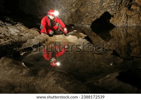 Reflection of a spelunker in a cave water pool. Carbide acetylene gas lamp on helmet illuminating the undeground